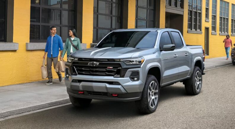 A silver 2023 Chevy Colorado Z71 is parked on the side of a city street.