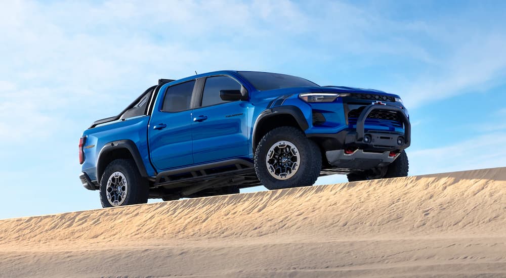 A blue 2024 Chevy Colorado ZR2 is parked on sand.