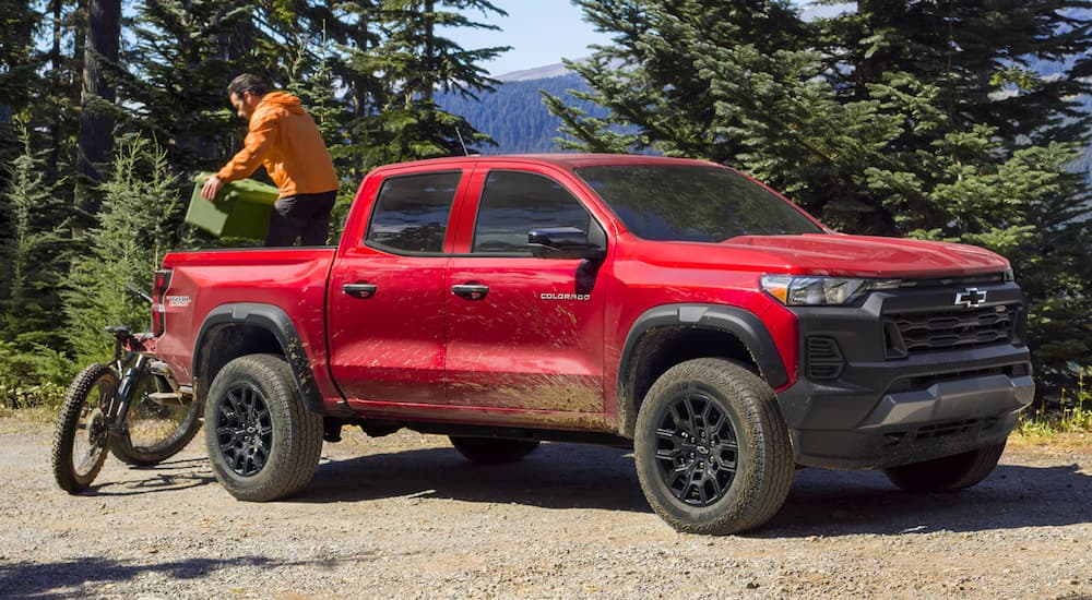 A red 2024 Chevy Colorado Trail Boss is parked on a dirt trail after leaving a Chevy dealer.