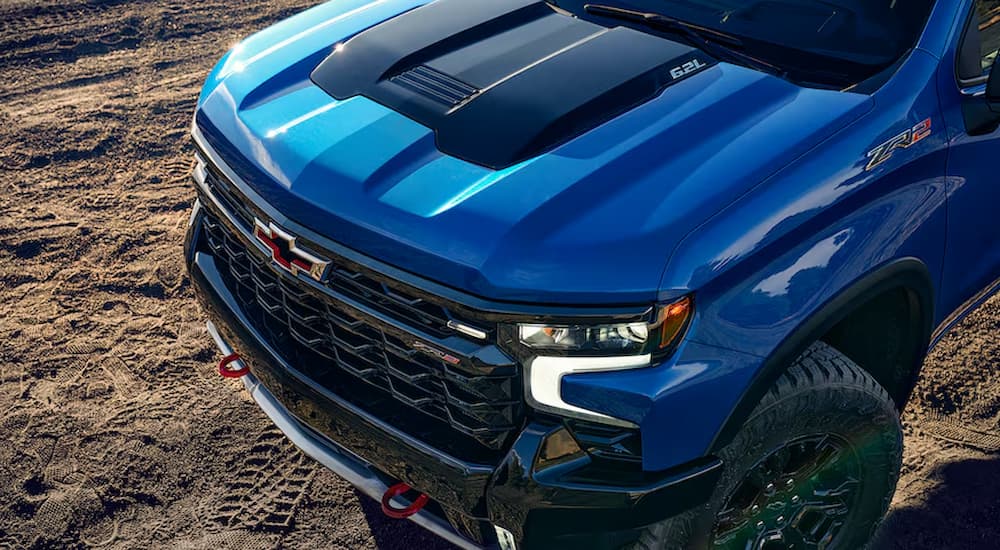 A close up of the front of a blue 2024 Chevy Silverado 1500 ZR2 parked on dirt.