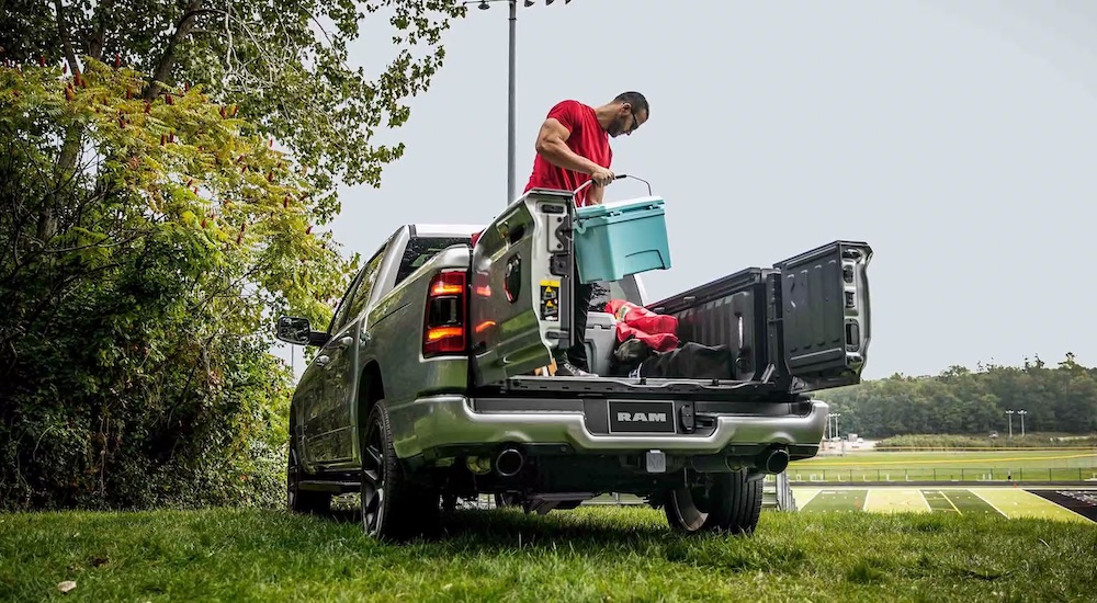 A man unloading gear from the bed of a silver 2024 RAM 1500.