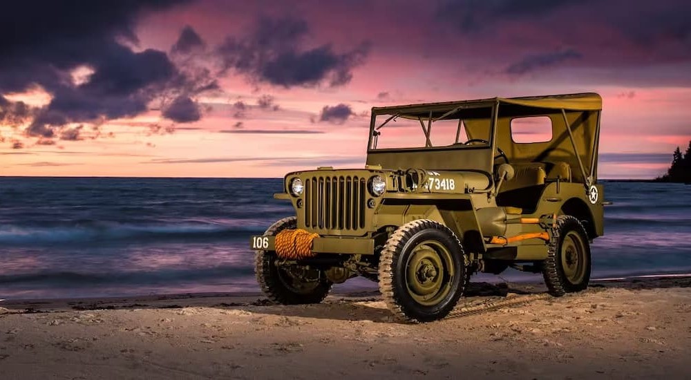 A green 1945 Jeep Willys MB is shown parked on a beach.