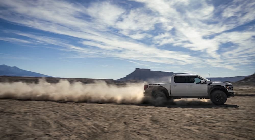 A white 2024 Ford F-150 Raptor R is shown driving off-road.
