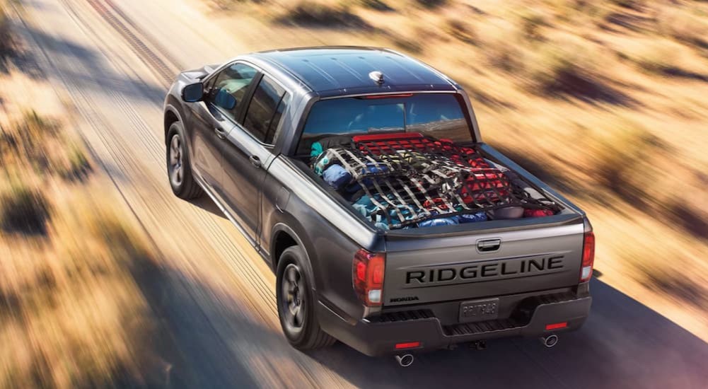 A gray 2024 Honda Ridgeline is shown driving off-road.