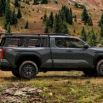 A side view of a black 2024 Toyota Tacoma TRD PreRunner parked off-road.