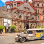 A silver Jeepney driving on an empty city road.