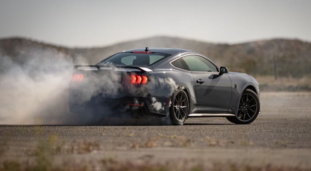 A black 2024 Ford Mustang Dark House doing burnouts.
