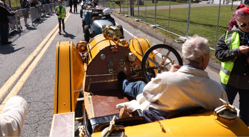A yellow 1912 Mercer 35 Raceabout is shown in a row of cars.