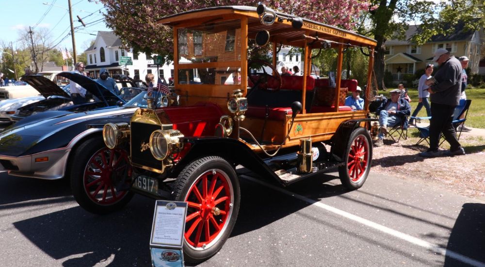 A red and wood grain 1914 Ford Model T Depot Hack is shown parked at a car show.