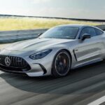 A silver 2024 Mercedes-AMG GT is shown driving on a racetrack.