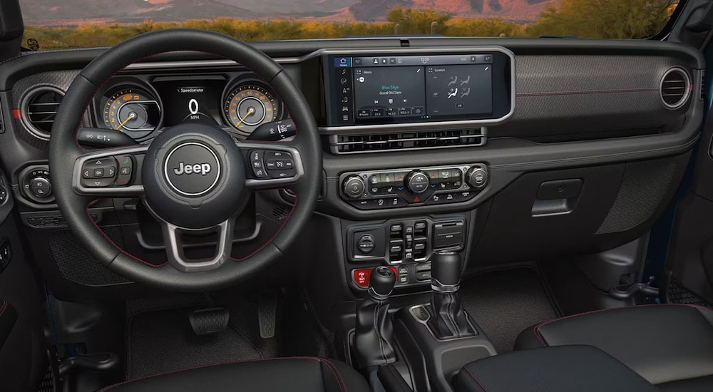 The black interior of a 2024 Jeep Gladiator for sale is shown from the driver's seat.