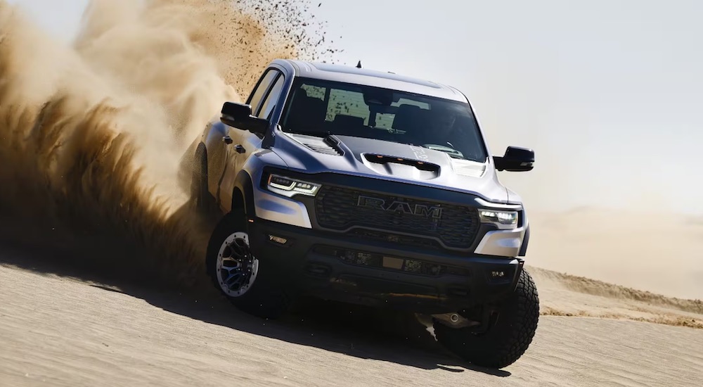 A white and black 2025 Ram 1500 RHO driving down a desert hill.