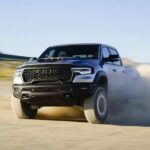 A white and black 2025 Ram 1500 RHO driving off-road in a desert.