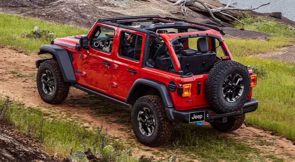 A red 2024 Jeep Wrangler Rubicon 392 Final Edition is shown driving off-road on a dirt path.