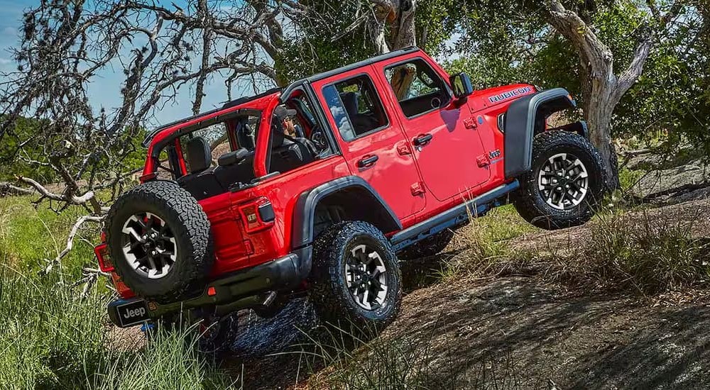 A red 2024 Wrangler Rubicon 392 Final Edition is shown driving uphill after visiting a Jeep dealer.