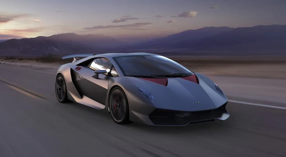 A gray 2011 Lamborghini Sesto Elemento is shown driving on a highway.