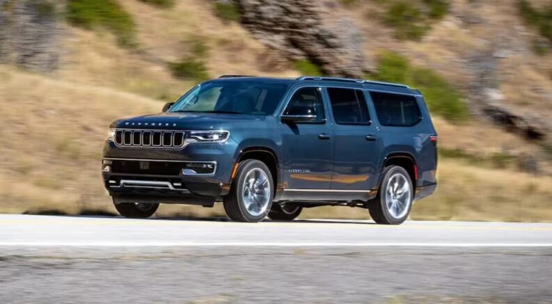 A blue 2024 Jeep Wagoneer is shown driving on a highway.