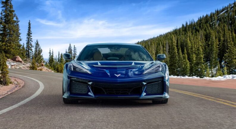 A blue 2025 Chevy Corvette ZR1 is shown rounding a corner.