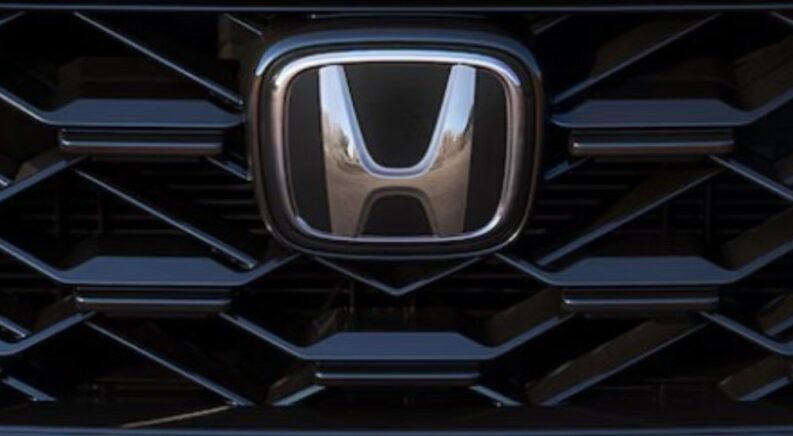 A close-up of a Honda Badge on the grille of a 2025 Honda CR-V is shown at a Honda dealer.