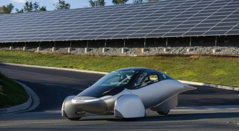 The black and silver Aptera Launch Edition is shown parked near solar panels.