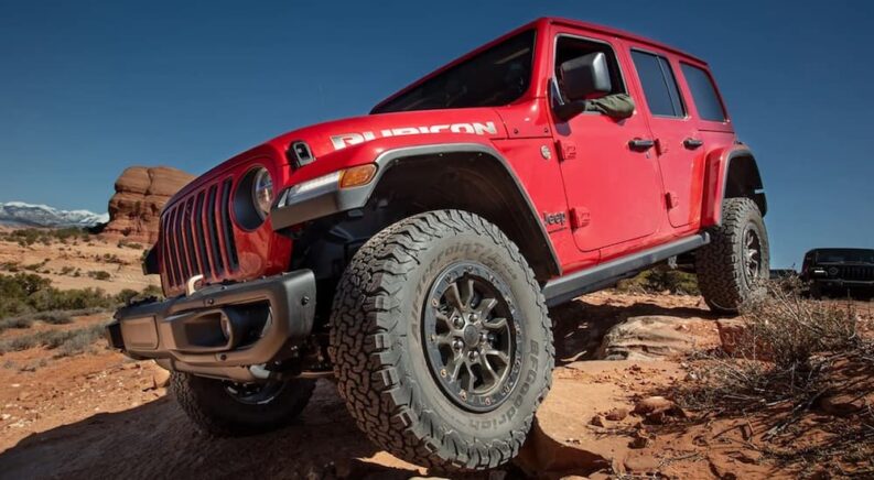 A red 2023 Jeep Wrangler Rubicon is shown from the front at an angle after leaving a used Jeep dealership.