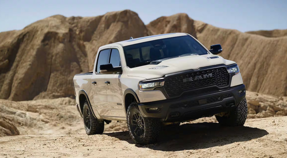 A white 2025 Ram 1500 Rebel X off-roading in a desert.