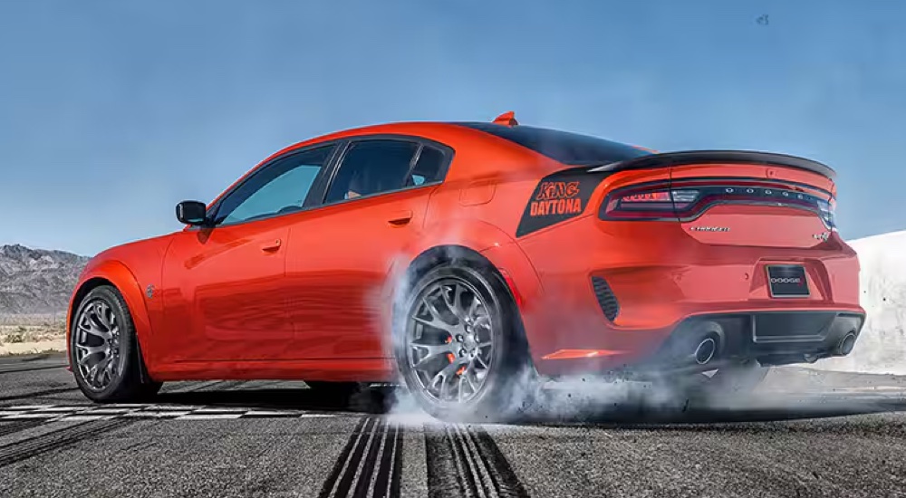 Rear view of an orange 2023 Dodge Charger King Daytona SRT doing a burnout.