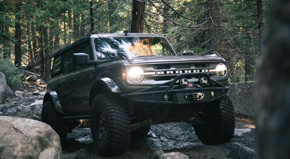 A black 2024 Ford Bronco KOH Edition driving in a forest.