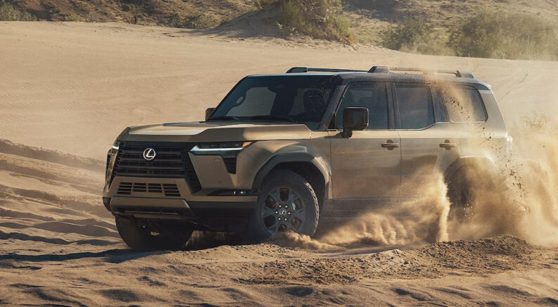 A tan 2024 Lexus GX 550 Overtrail+ kicking up sand while off-roading.