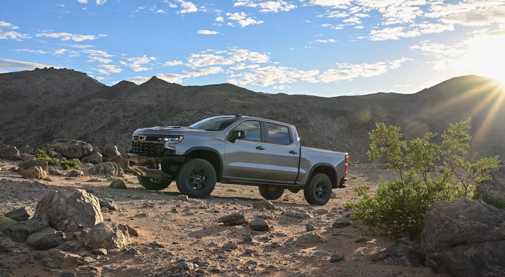 A grey 2023 Chevy Silverado 1500 ZR2 is shown from the side while parked off-road after leaving a dealer that has used trucks for sale.