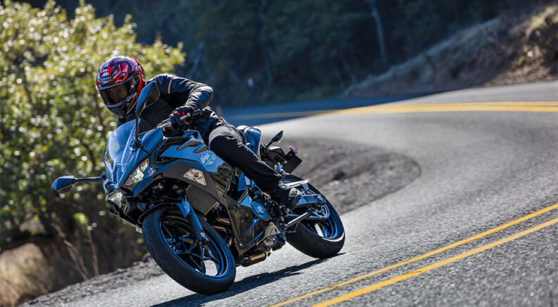 A black 2024 Kawasaki Ninja 500 is shown from the side while cornering after leaving a dealer that has a Kawasaki for sale.