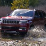 A red 2023 Jeep Wagoneer is shown splashing through a river after leaving a Jeep dealer.