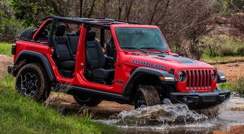 A red 2023 Jeep Wrangler Rubicon 4xe is shown from the side after leaving a dealer that has used Jeeps for sale.