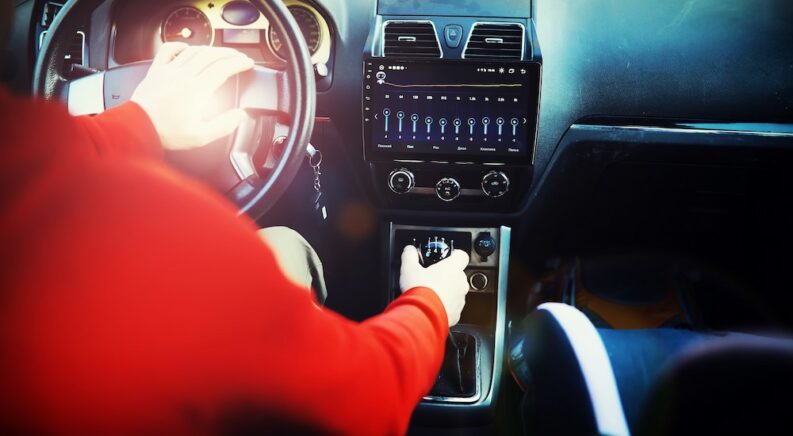 A person is shown driving a manual vehicle.