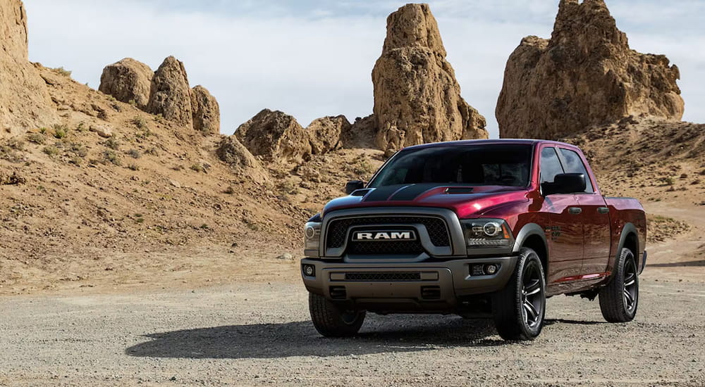 A red 2025 Ram 1500 Classic Warlock parked off-road in a desert and angled left.