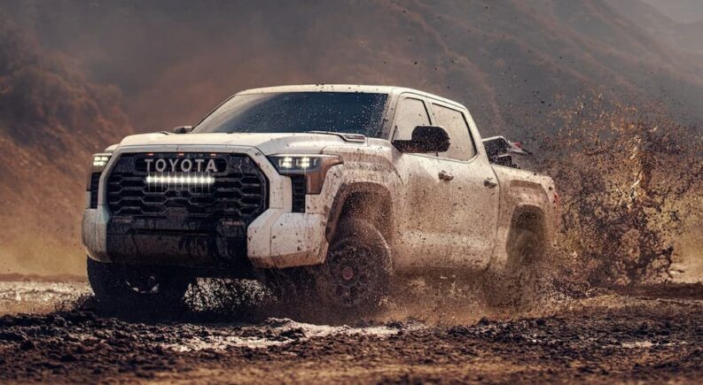 A white 2025 Toyota Tundra TRD Pro CrewMax is shown driving off-road after viewing a Toyota Tundra for sale.