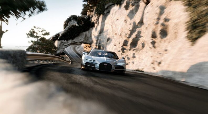 A grey 2026 Bugatti Tourbillon is shown driving on a winding road.