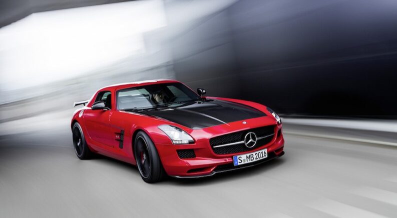 A popular used Mercedes-Benz for sale, a red 2014 Mercedes-Benz SLS AMG GT Final Edition, is shown driving on a city street.