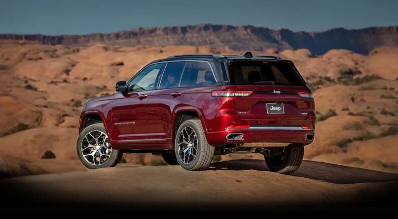 A red 2022 Jeep Grand Cherokee is shown from the rear at an angle after leaving a dealer that has a used Jeep for sale.