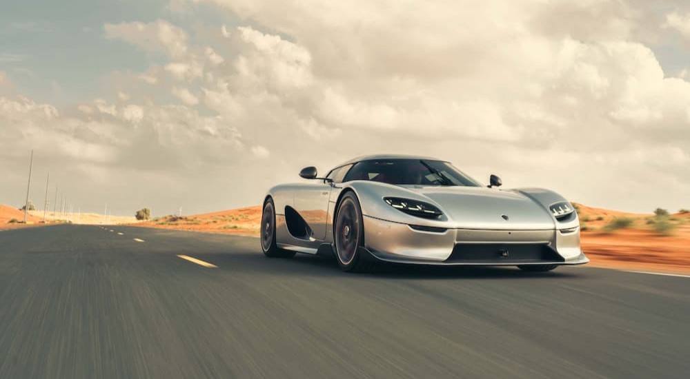 A silver 2024 Koenigsegg CC850 is shown driving on a highway.