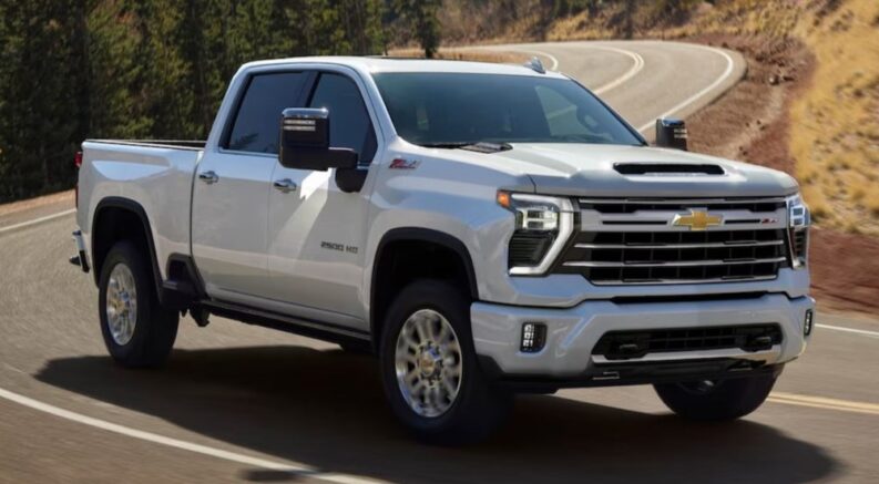 A white 2025 Chevy Silverado 2500 Z71 is shown driving on a highway.