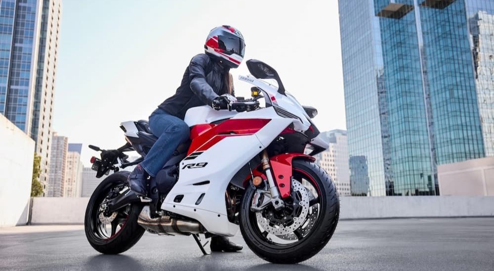 A person is shown on a parked white and red 2025 Yamaha R9.