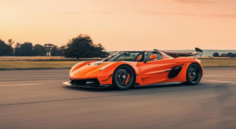 An orange 2024 Koenigsegg Jesko is shown driving on a track.