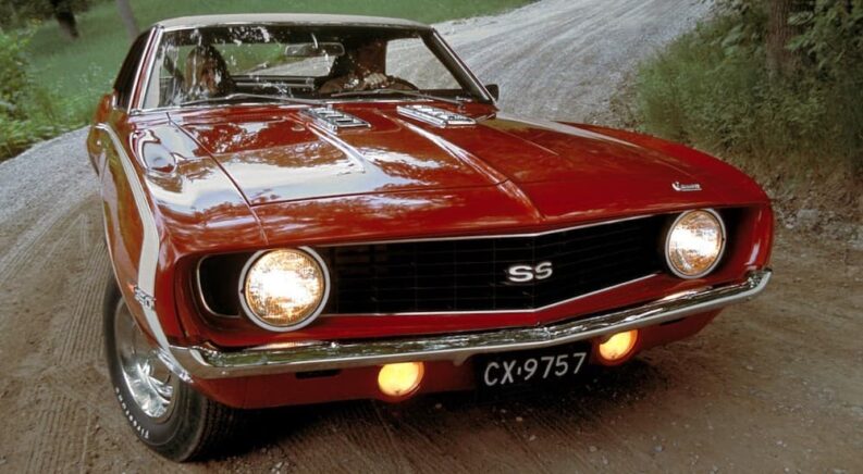 A red 1969 Chevy Camaro SS Coupe is shown driving after viewing used cars for sale.