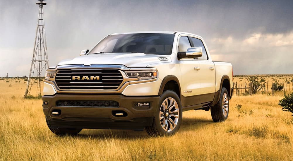 A white 2020 Ram 1500 Laramie Longhorn parked on a wheat field and angled left.