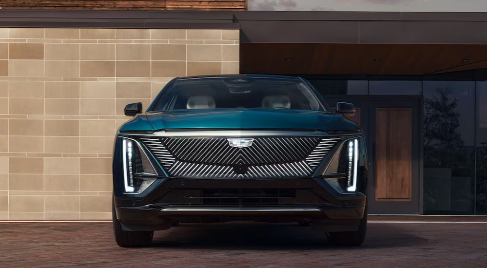 A green 2025 Cadillac LYRIQ is shown parked near a modern house.