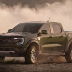 An army green 2024 Ford Ranger Raptor kicking up sand while off-roading.