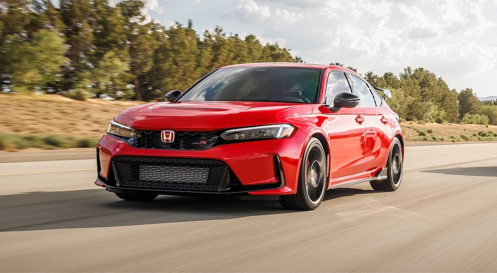 A red 2025 Honda Civic Type R driving from a Honda dealer.