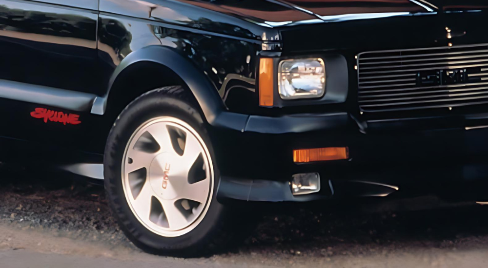 Close-up of the front wheel and grille of a black 1991 GMC Syclone.