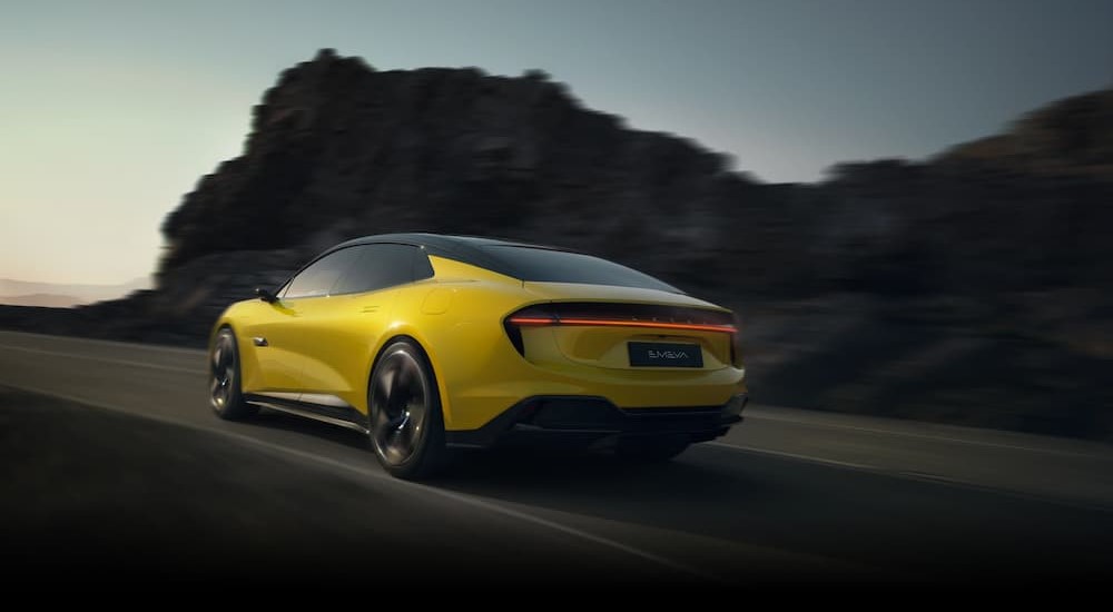 A yellow 2024 Lotus Emeya is shown driving on a highway.